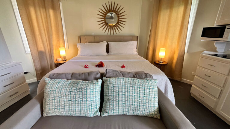 King bed with soft lighting and decorative pillows in the Pelican Suite at Arawak Beach Club in Anguilla