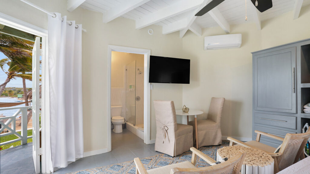 Arawak_suite-3-5_1600 Living area with armchairs and wall-mounted TV in the Parrot Fish Suite at Arawak Beach Club in Anguilla