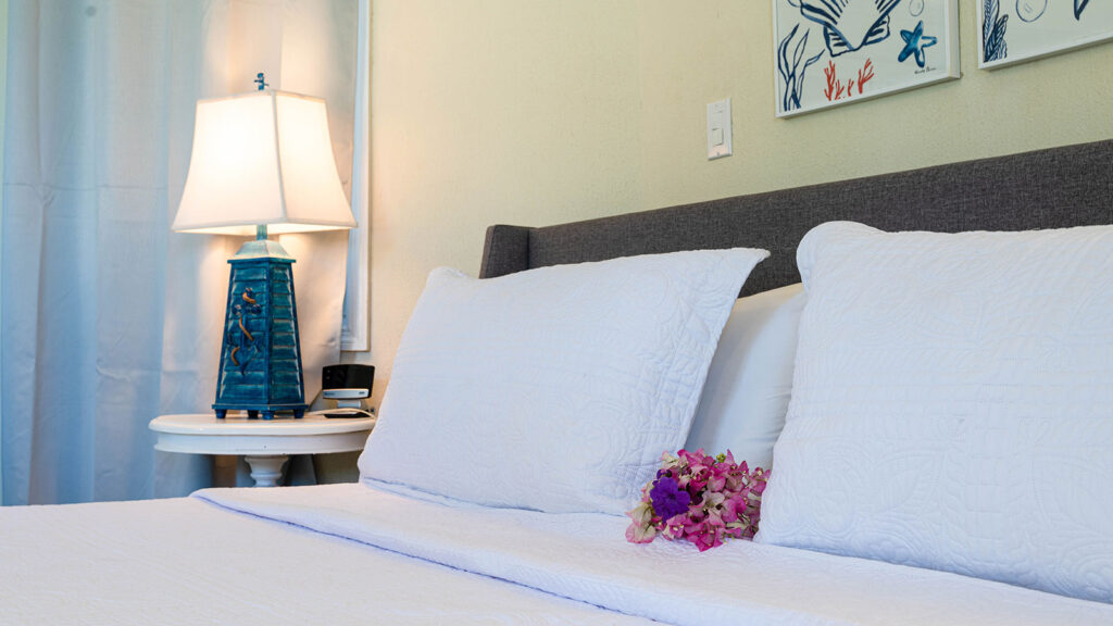 Arawak_suite-4-2_1600 Close-up of king bed with soft linens and bedside lighting in the Blue Horizon Suite at Arawak Beach Club in Anguilla