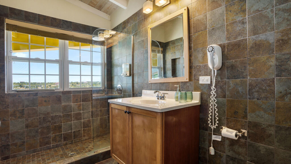 Arawak_suite-7-3_1600 Bathroom vanity with dark tile and large mirror in the Sunset Suite at Arawak Beach Club in Anguilla