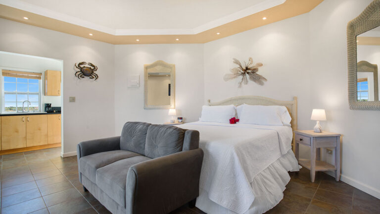 King bed with cozy sitting area and soft lighting in the Sea Mist Suite at Arawak Beach Club in Anguilla