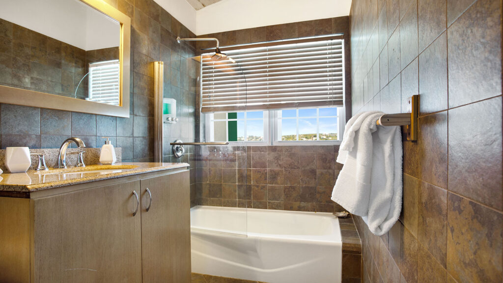 Arawak_suite-9-3_1600 Bathroom with tiled walk-in shower and large window in the Sea View Suite at Arawak Beach Club in Anguilla